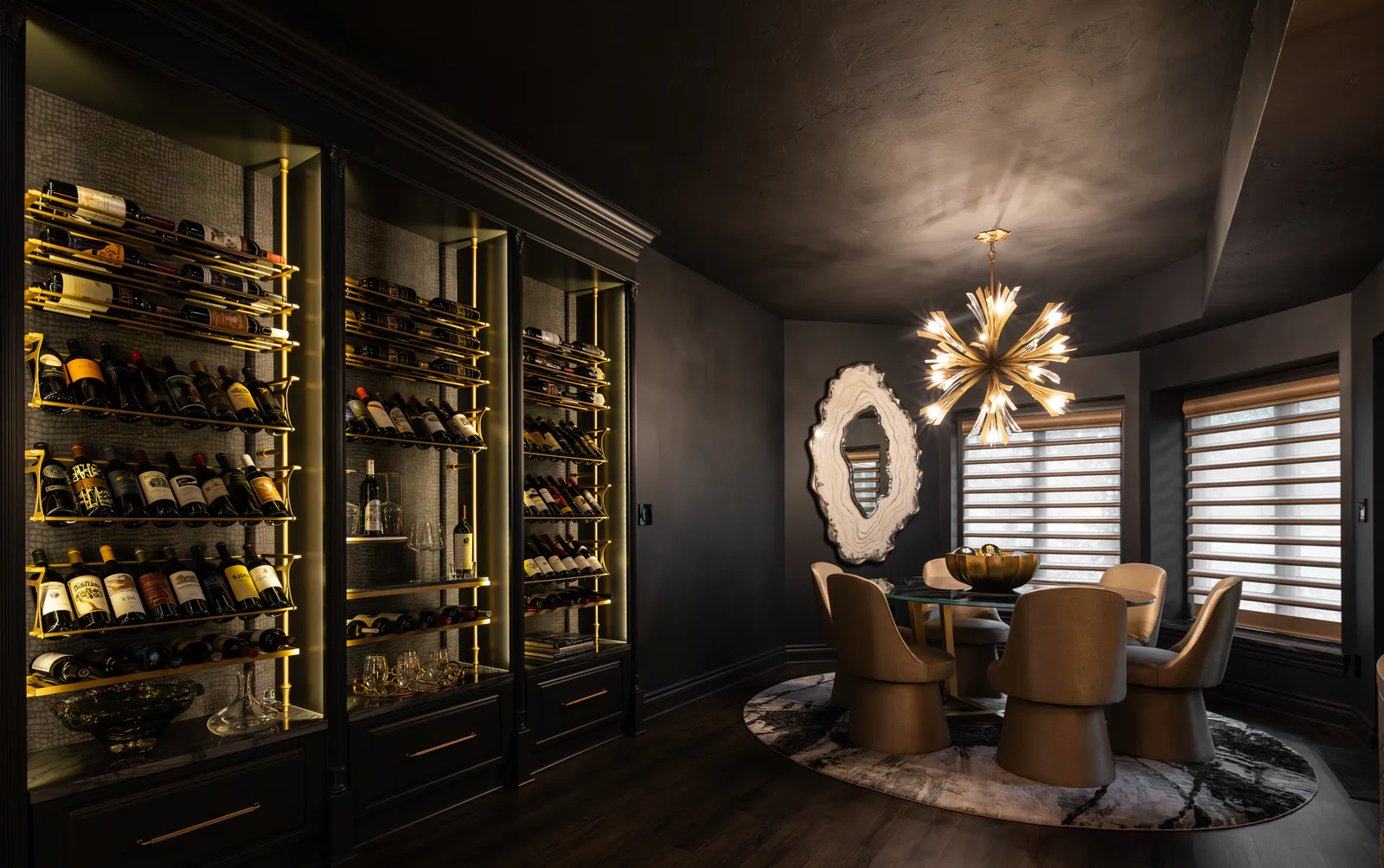 A dark wine room with illuminated brass bottle displays and a round dining table.